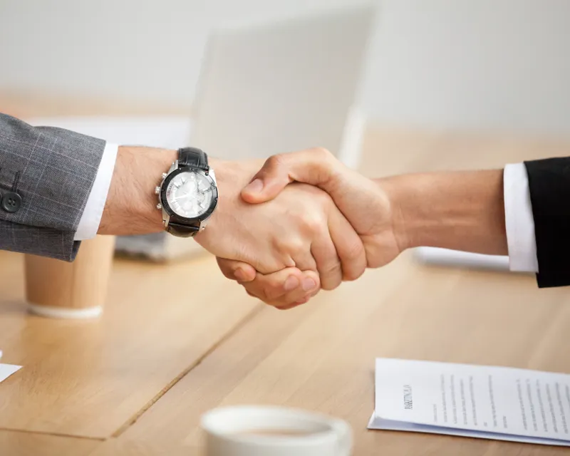 Aperto de mão entre cliente e consultor ao fechar a contratação